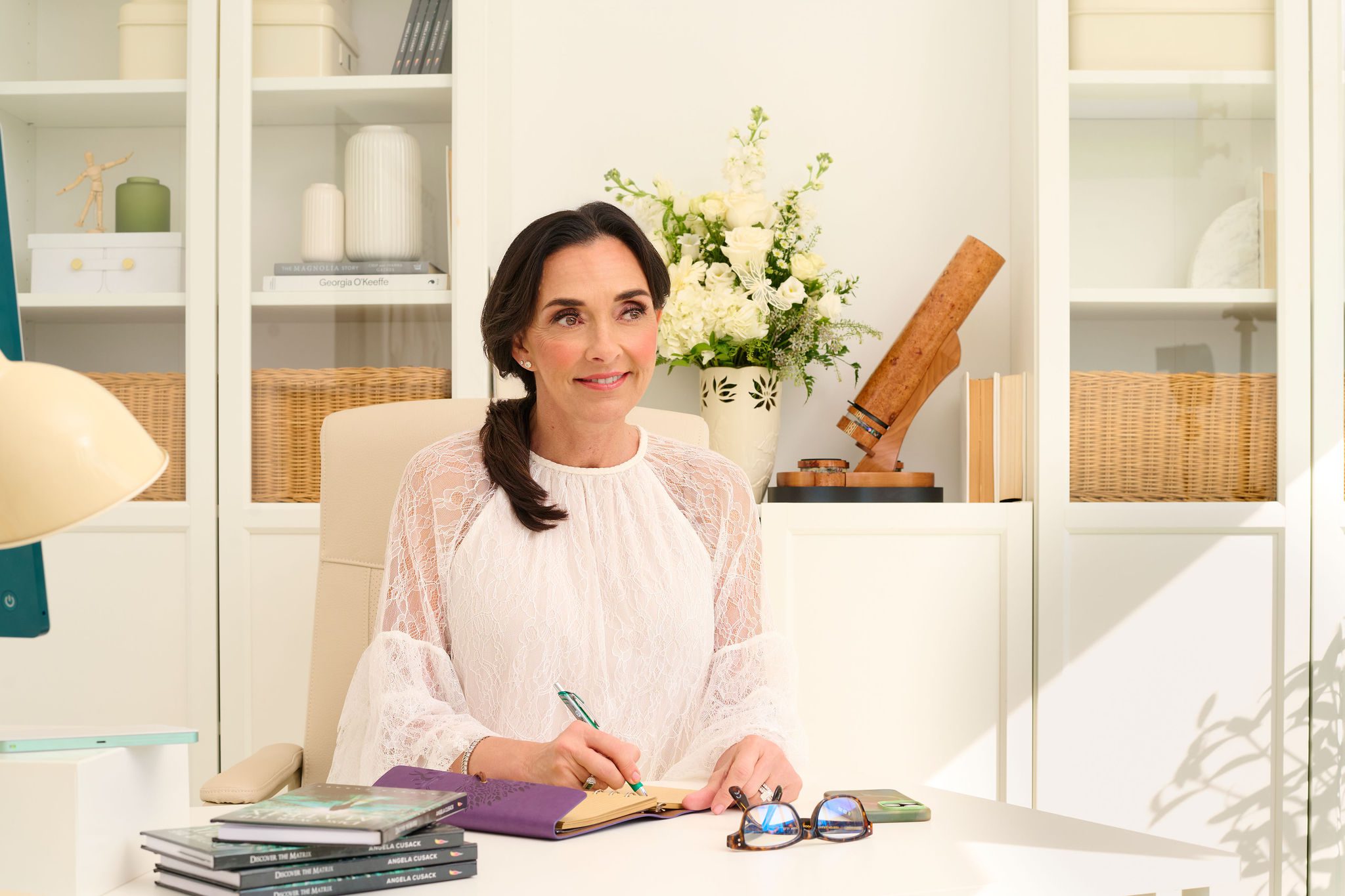 Angela Cusack in a white blouse sitting at her desk