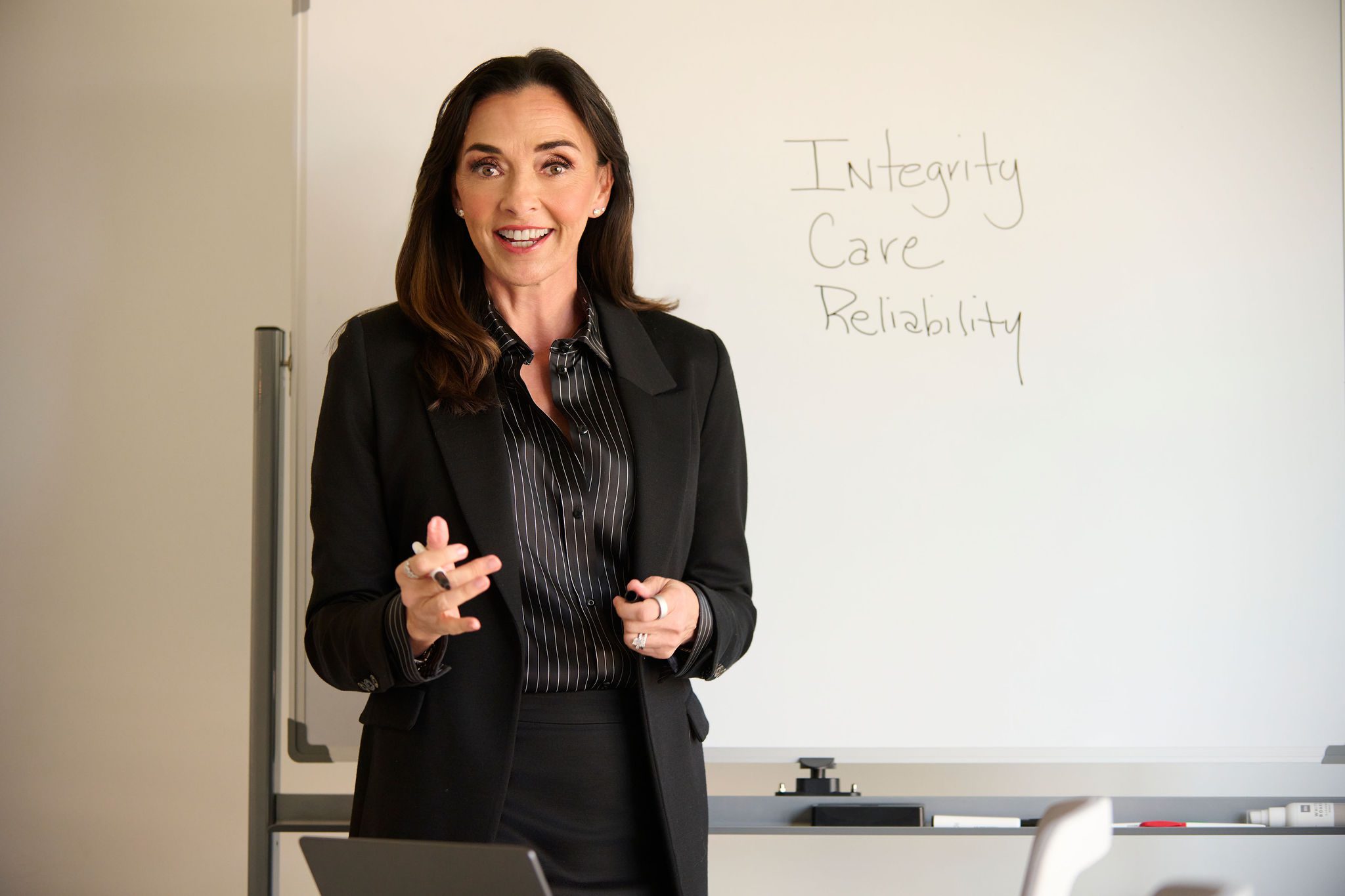 Angela Cusack in all black in front of a whiteboard